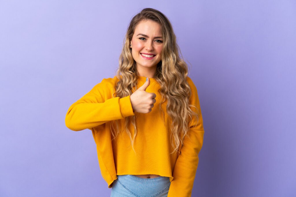 młoda kobieta pokazuje gestem kciukiem do góry